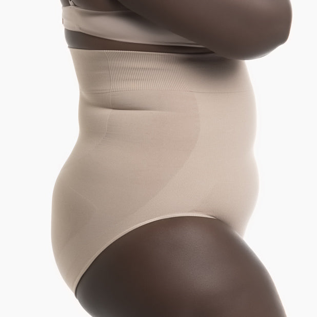 Right side view of women’s powder high-waisted shapewear brief worn by curvy model