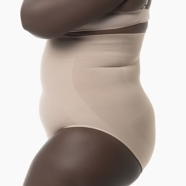 Left side view of women’s powder high-waisted shapewear brief worn by curvy model