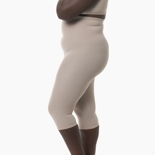Left side view of women’s powder high-waist anti-cellulite capri shapewear worn by curvy model
