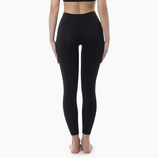 Back view of women’s black mid-waisted tummy control leggings worn by model